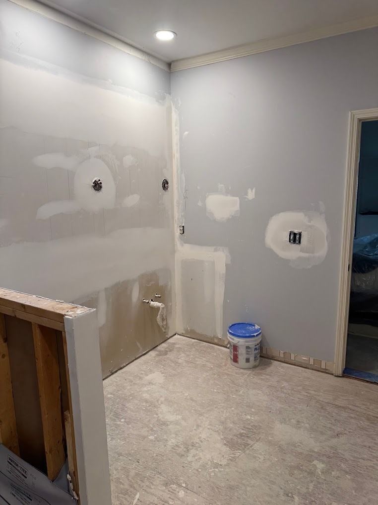 Partially finished room with gray drywall, spackle patches, and a paint bucket on the floor