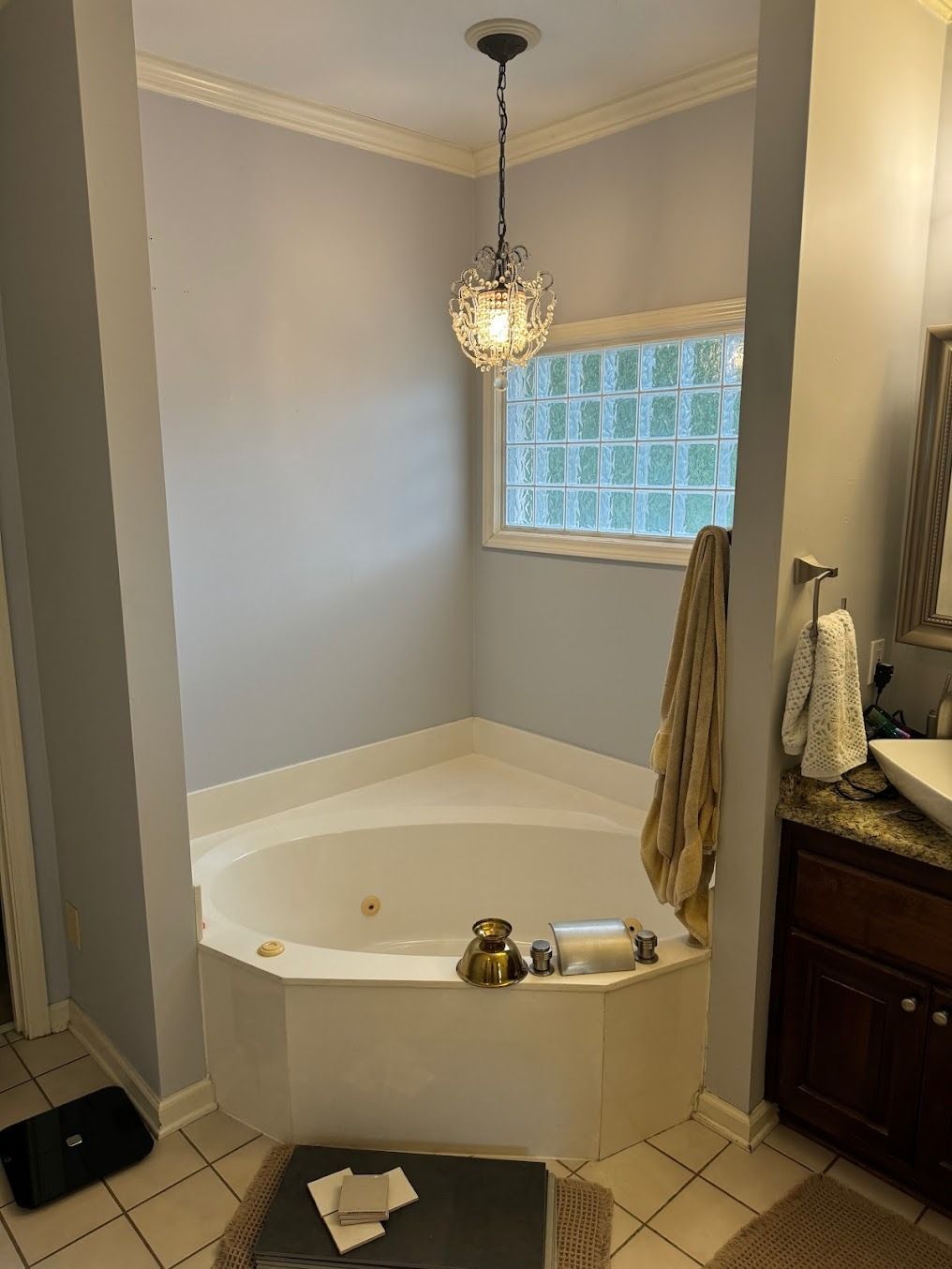 Small bathroom with a white corner soaking tub, window, pendant light, and gray walls