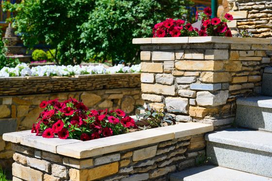 Stone garden steps with stacked planter boxes of red flowers and greenery