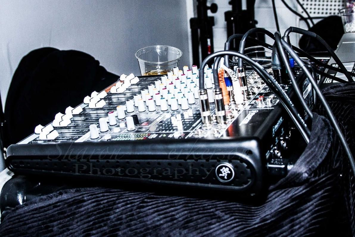 Audio mixing console with many cables on a table, lit by blue and white lights