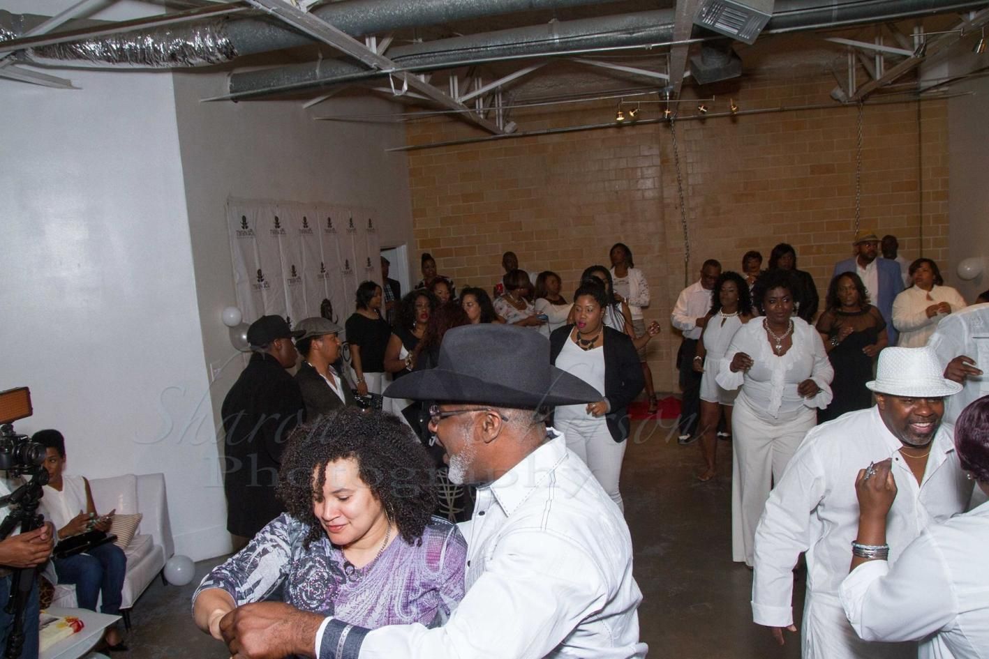 People dancing at an indoor party, with guests seated and standing in the background.