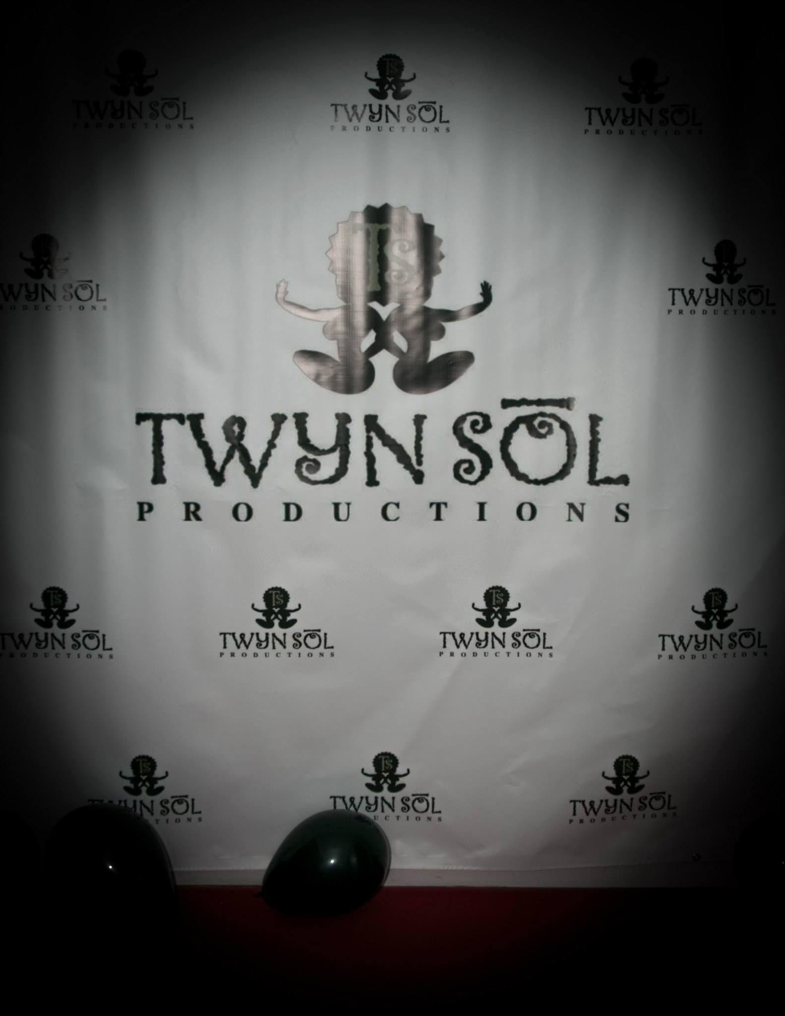 Twyn Sol Productions logo with stylized face mask on a dark, smoky background with spotlights