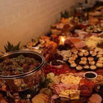 Buffet table with assorted appetizers and desserts arranged along a wall