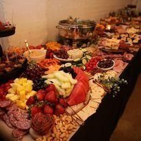 Buffet table with platters of fruit, cheese, meats, and desserts arranged for a party