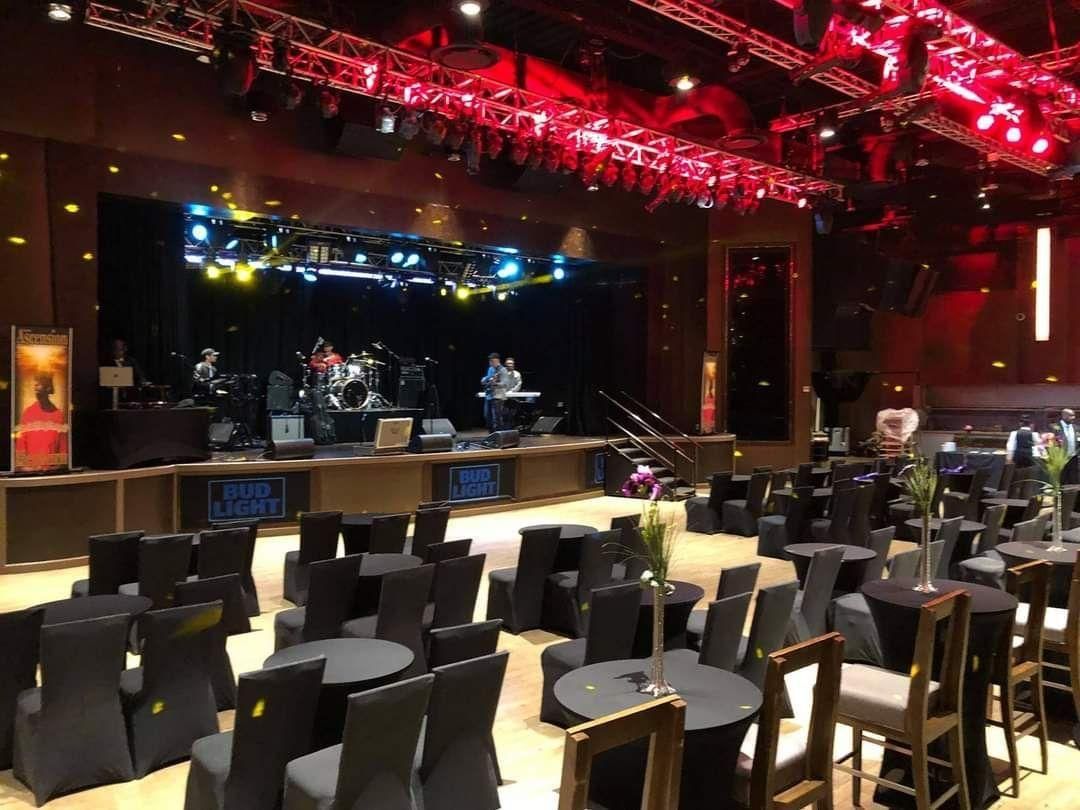 Empty concert venue with stage, red lighting, and rows of chairs facing the band setup
