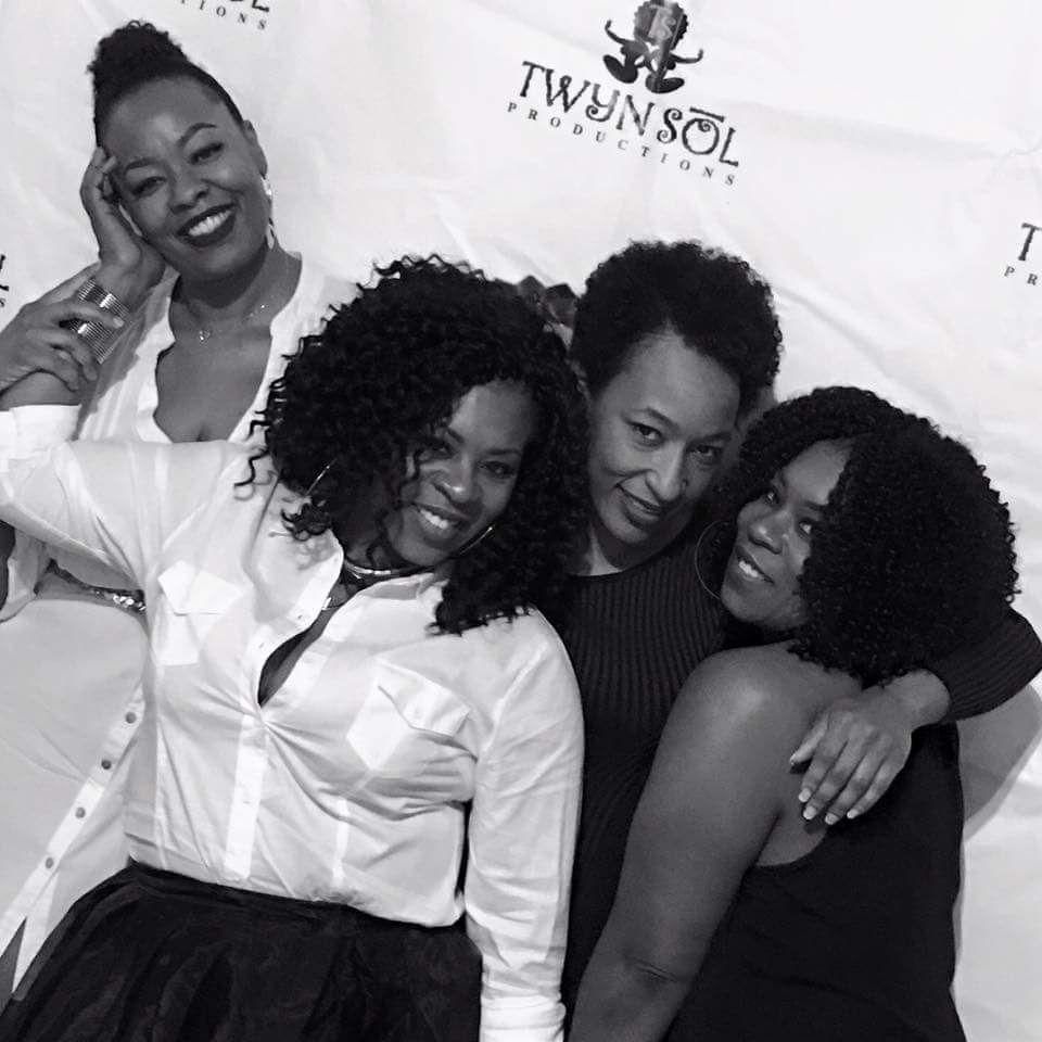 Four people smiling and posing together at a Twynsol-branded event backdrop.
