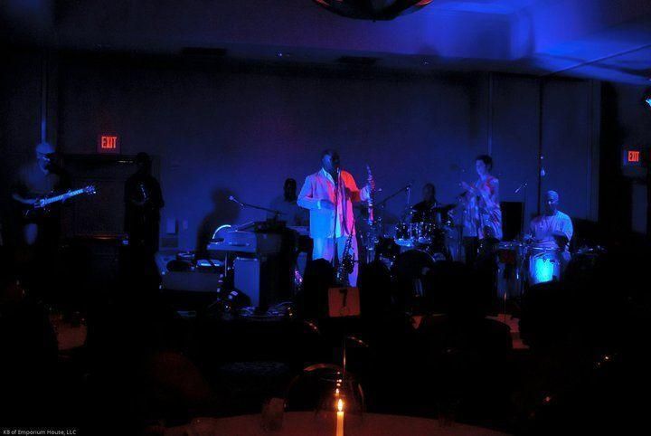 Dimly lit band performing onstage under blue and red lights in a dark venue