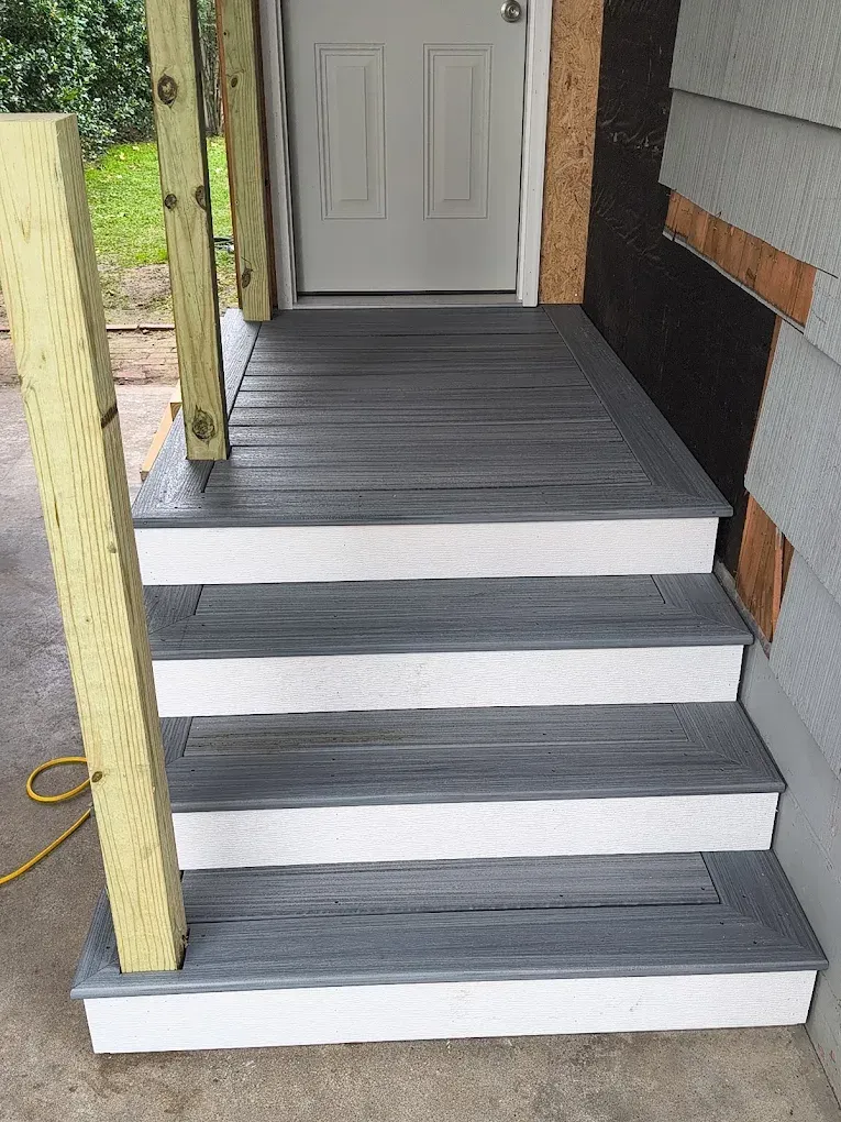 Front porch stairs with gray treads and white risers leading to a white door