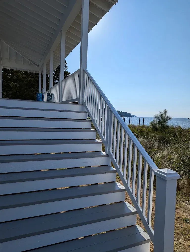 White staircase on a seaside porch with blue sky and ocean view