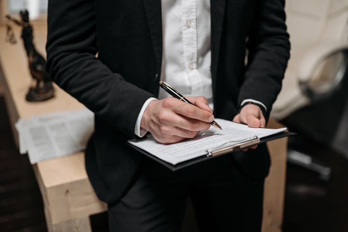 A person in a black blazer holding a clipboard.