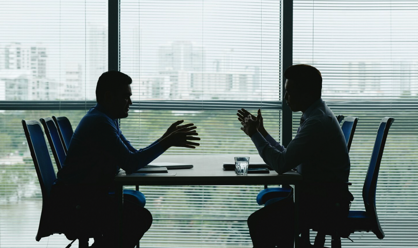 Two business owners facing each other during a tense discussion about an ownership dispute.