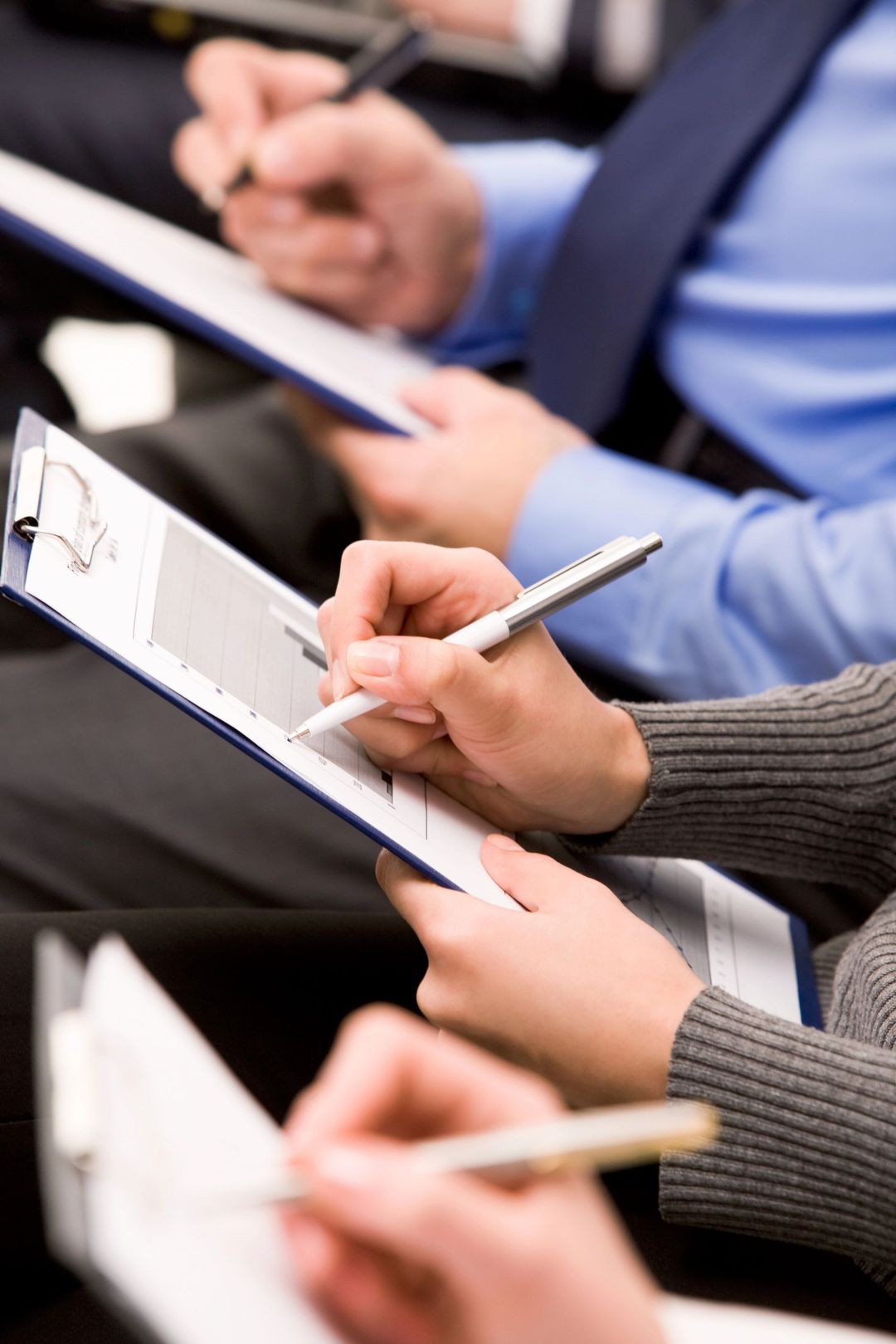 Persone che prendono appunti su dei blocchi per appunti durante una riunione o una lezione.