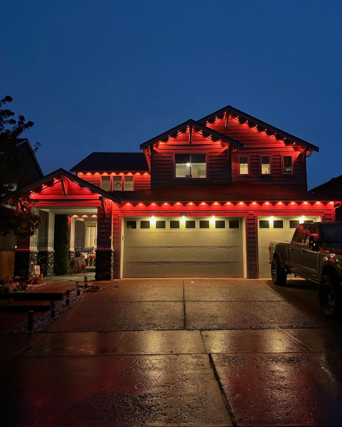 Large two-story home with red holiday lights along the roofline.