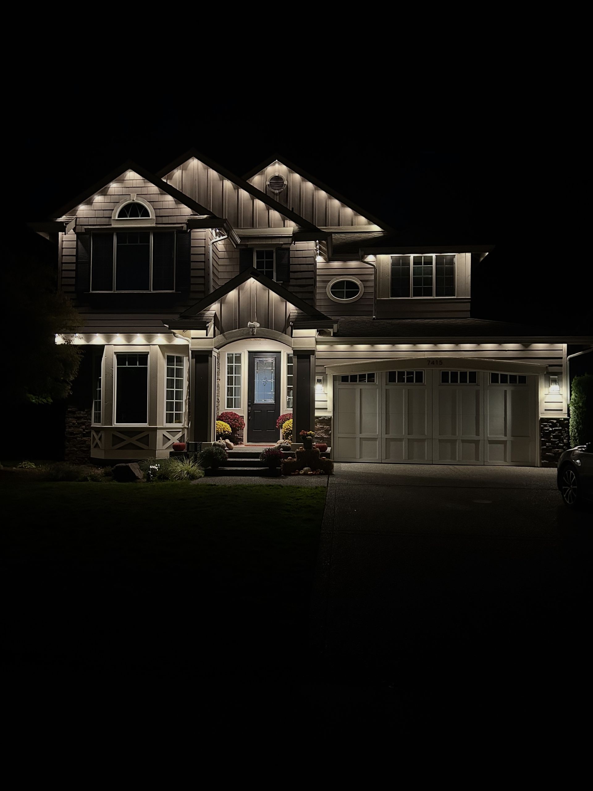 Large two-story house illuminated by exterior architectural lighting at night.