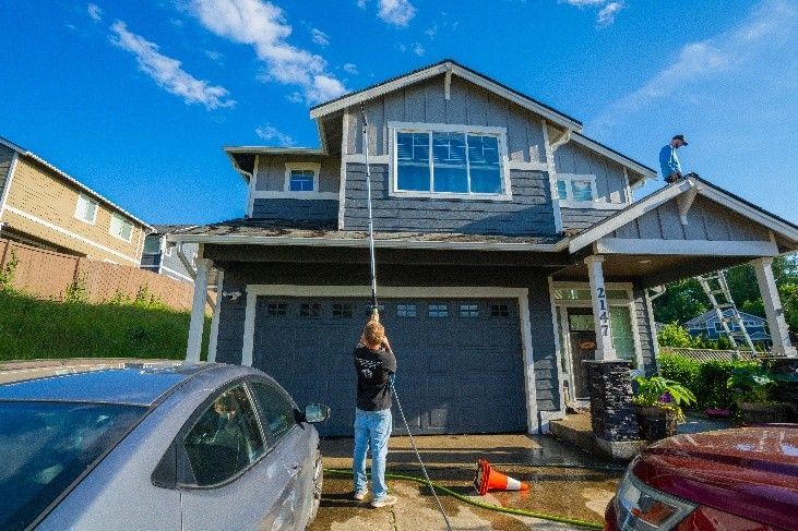Specialist using a water-fed pole to rinse second-story windows.