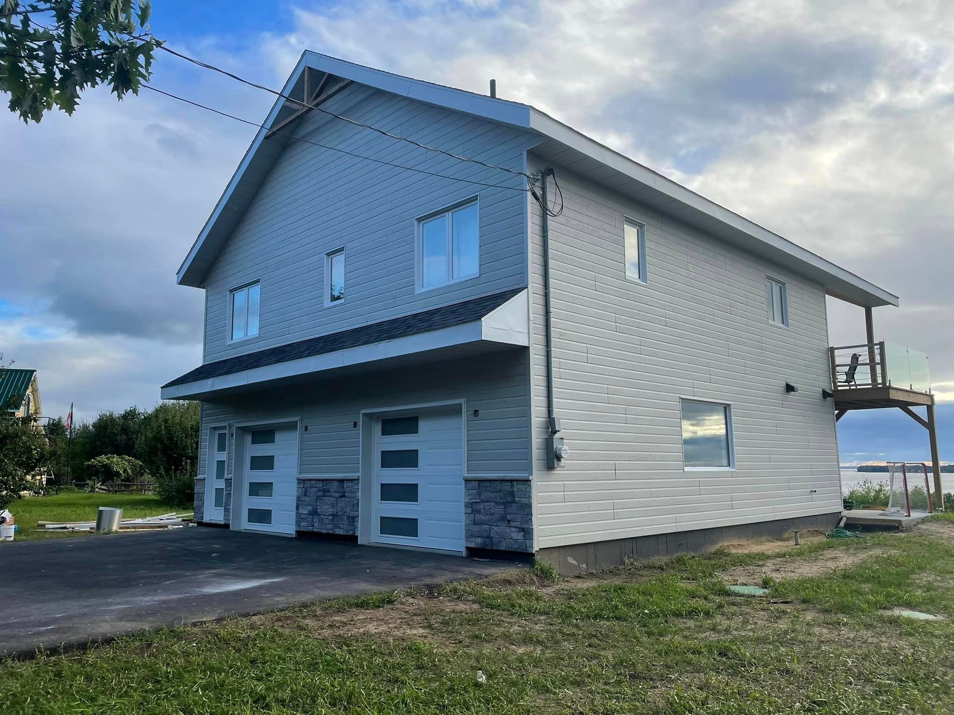 Une grande maison blanche avec deux garages et un balcon.