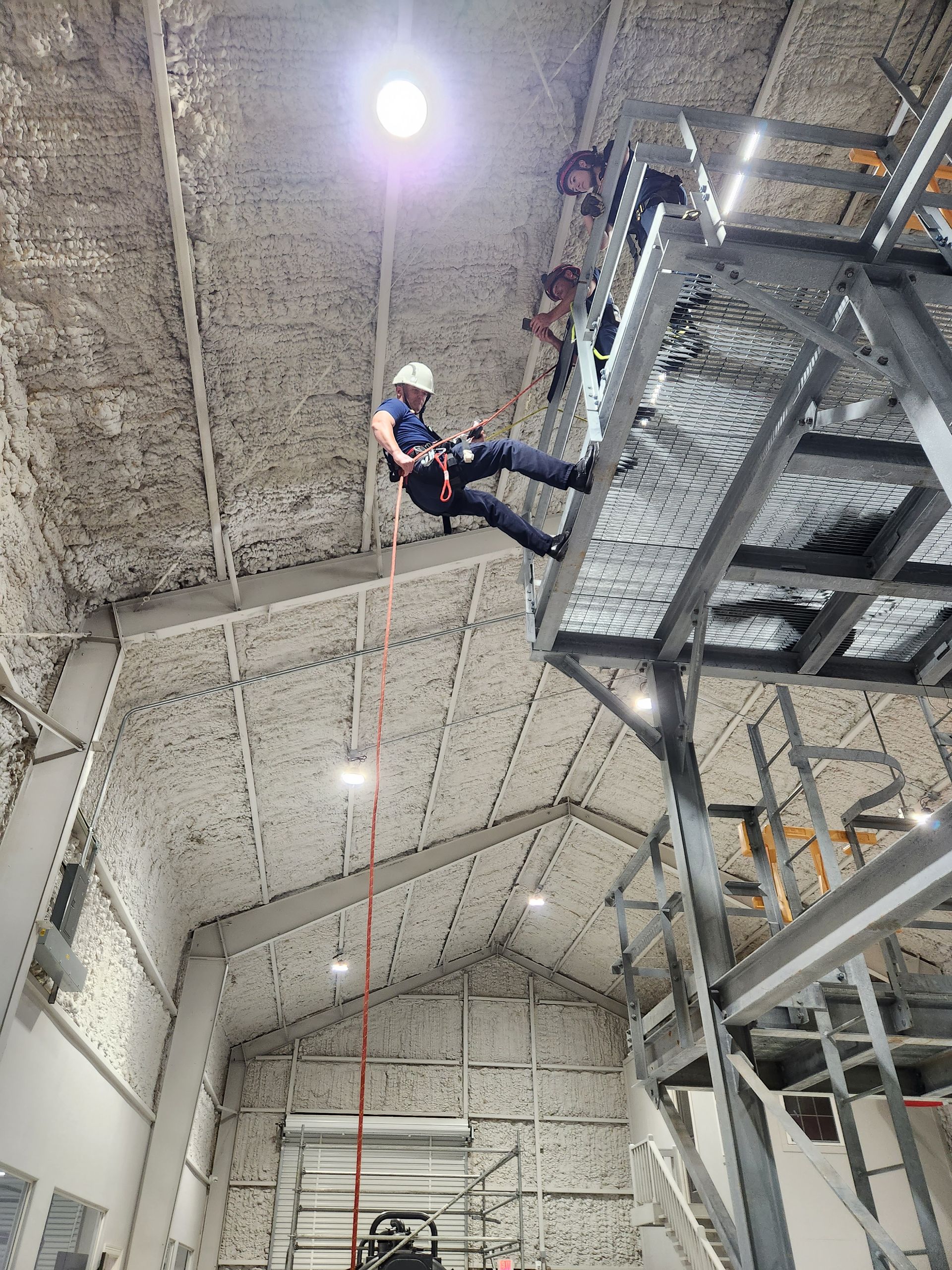 A man is climbing a rope in a building.