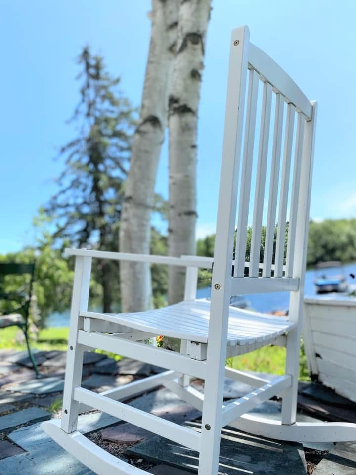 White wooden chair on a sunny patio with trees in the background