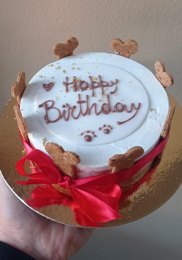 Torta di compleanno per cani con nastro rosso, biscotti a forma di cuore e scritta