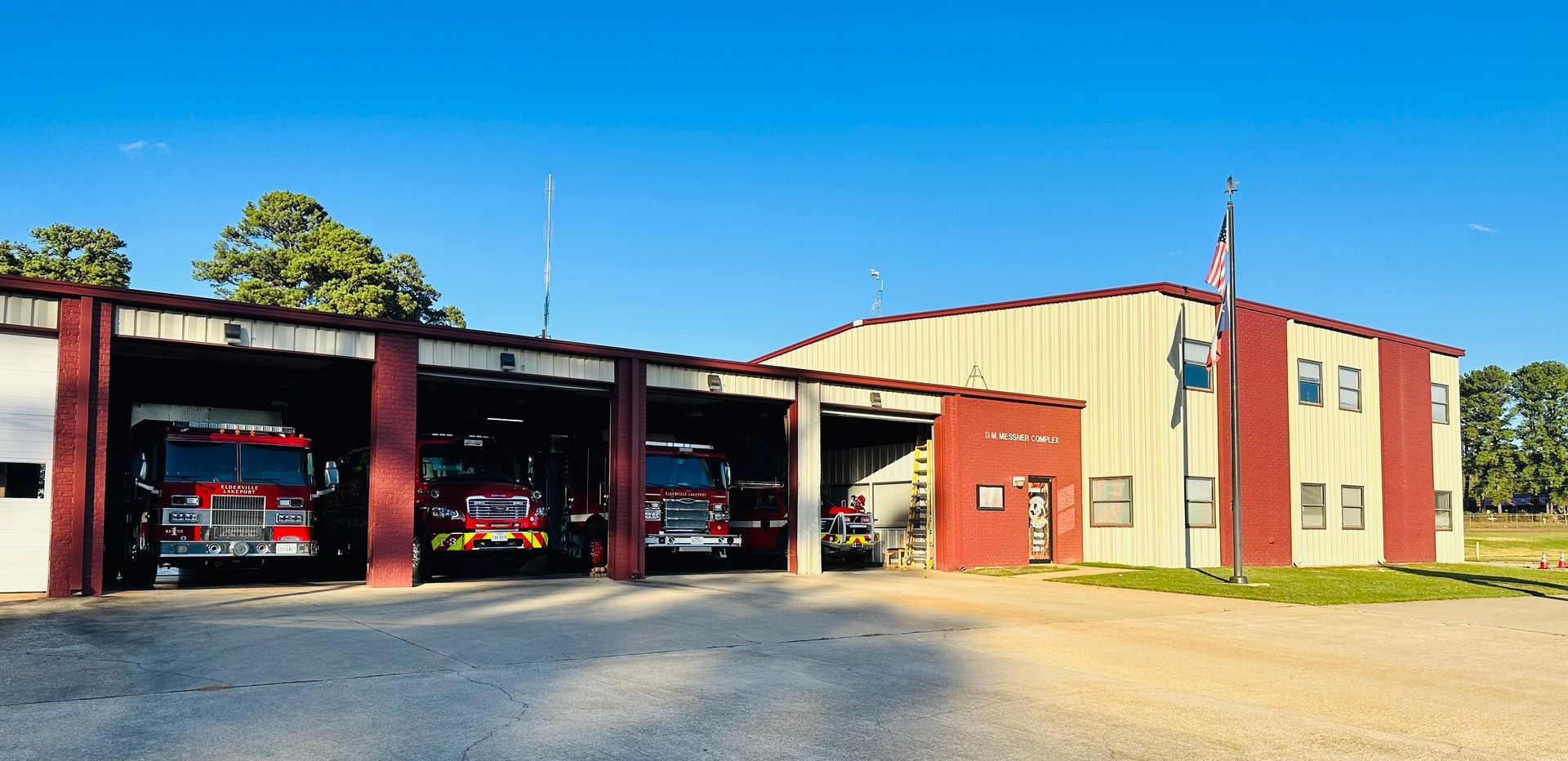 A fire station with a lot of fire trucks parked in front of it.