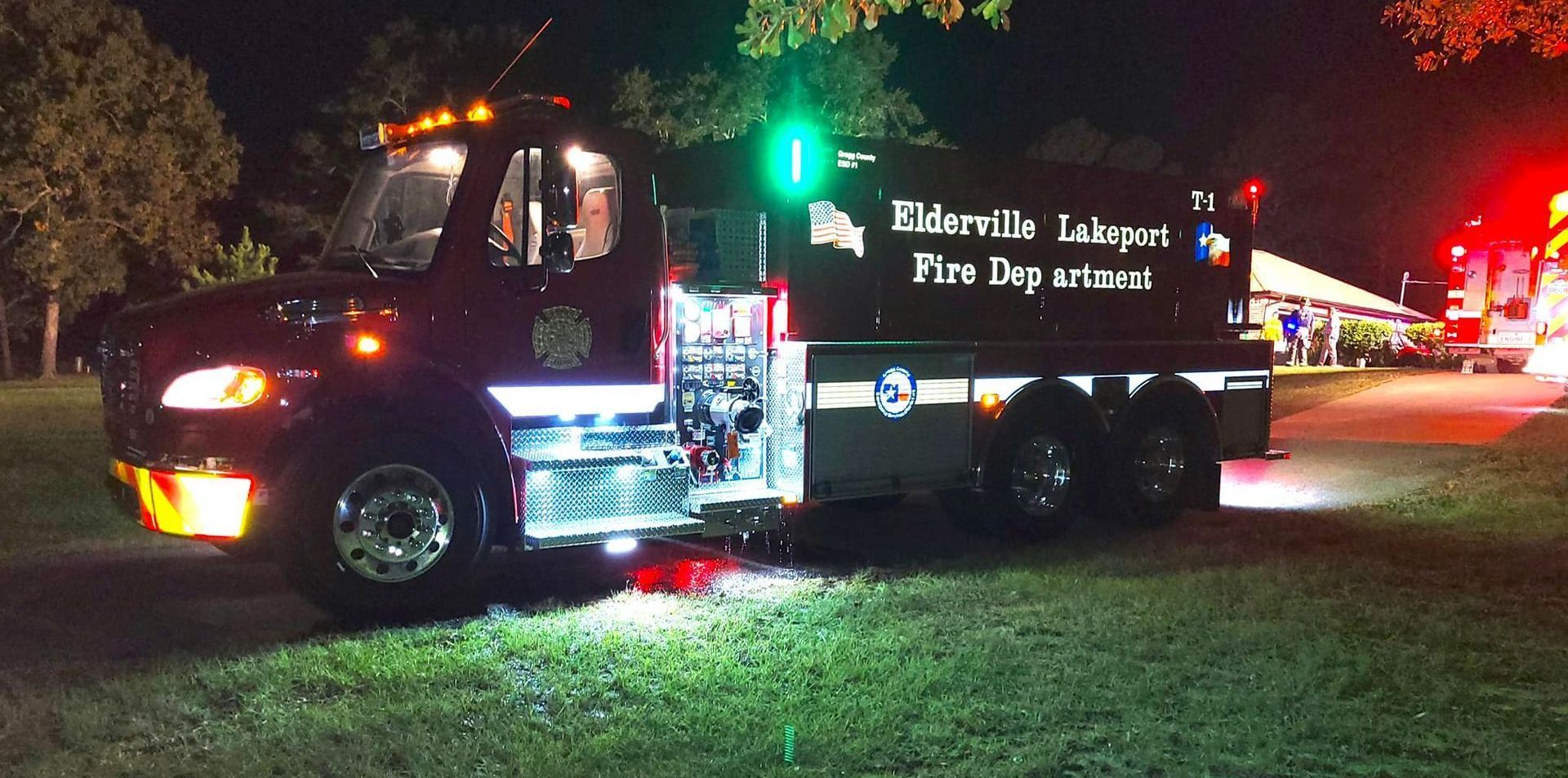 A fire truck is parked in the grass at night