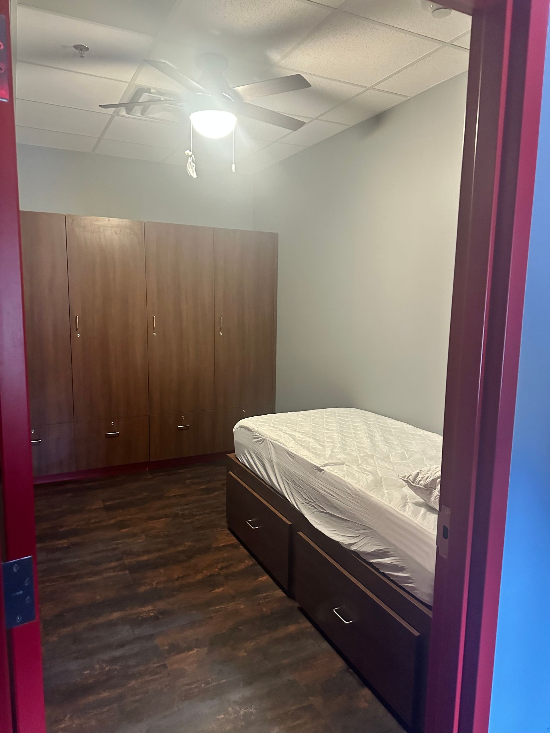 A bedroom with a bed and a red door.