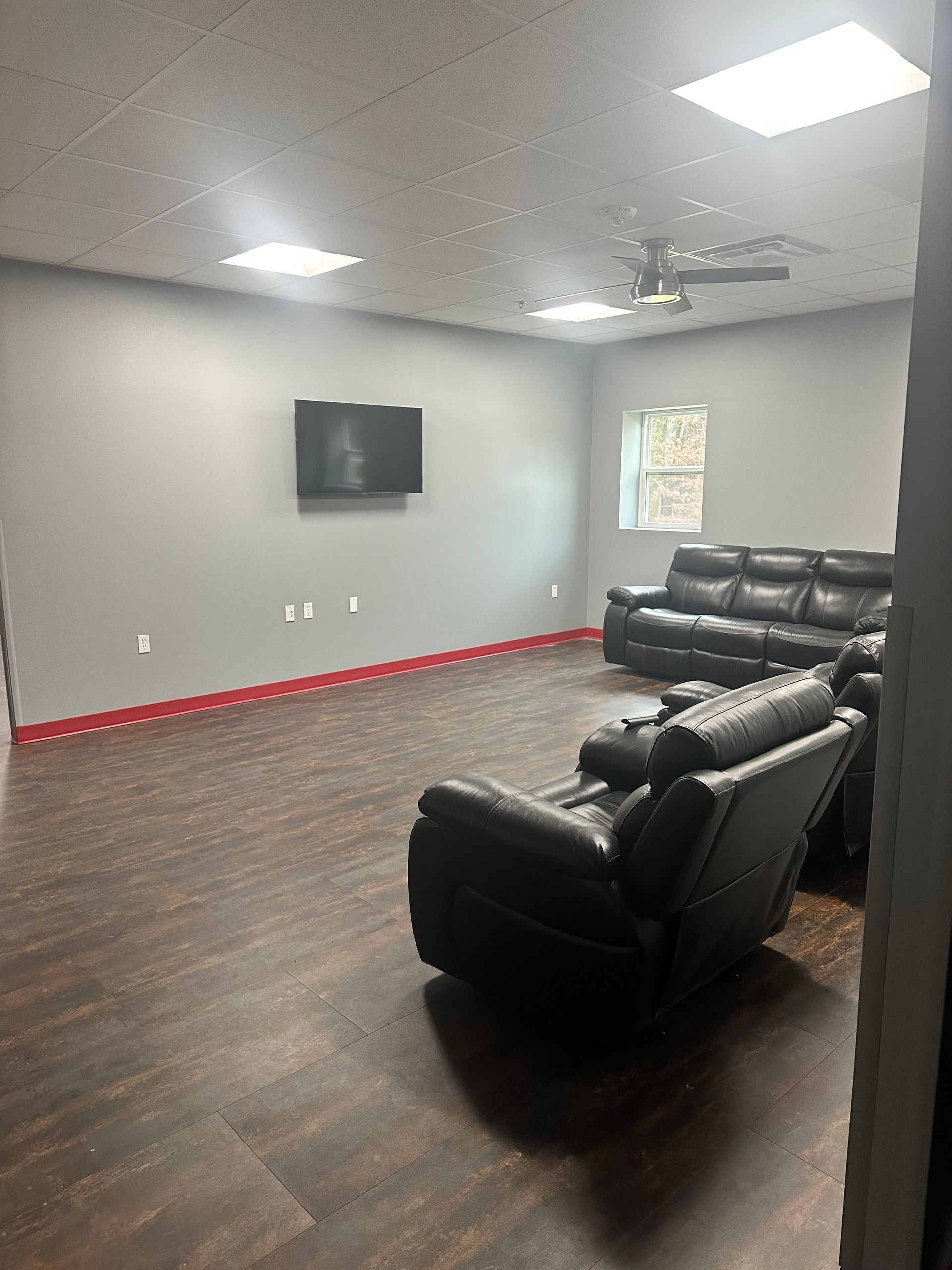 A living room with a couch and chairs and a flat screen tv on the wall.