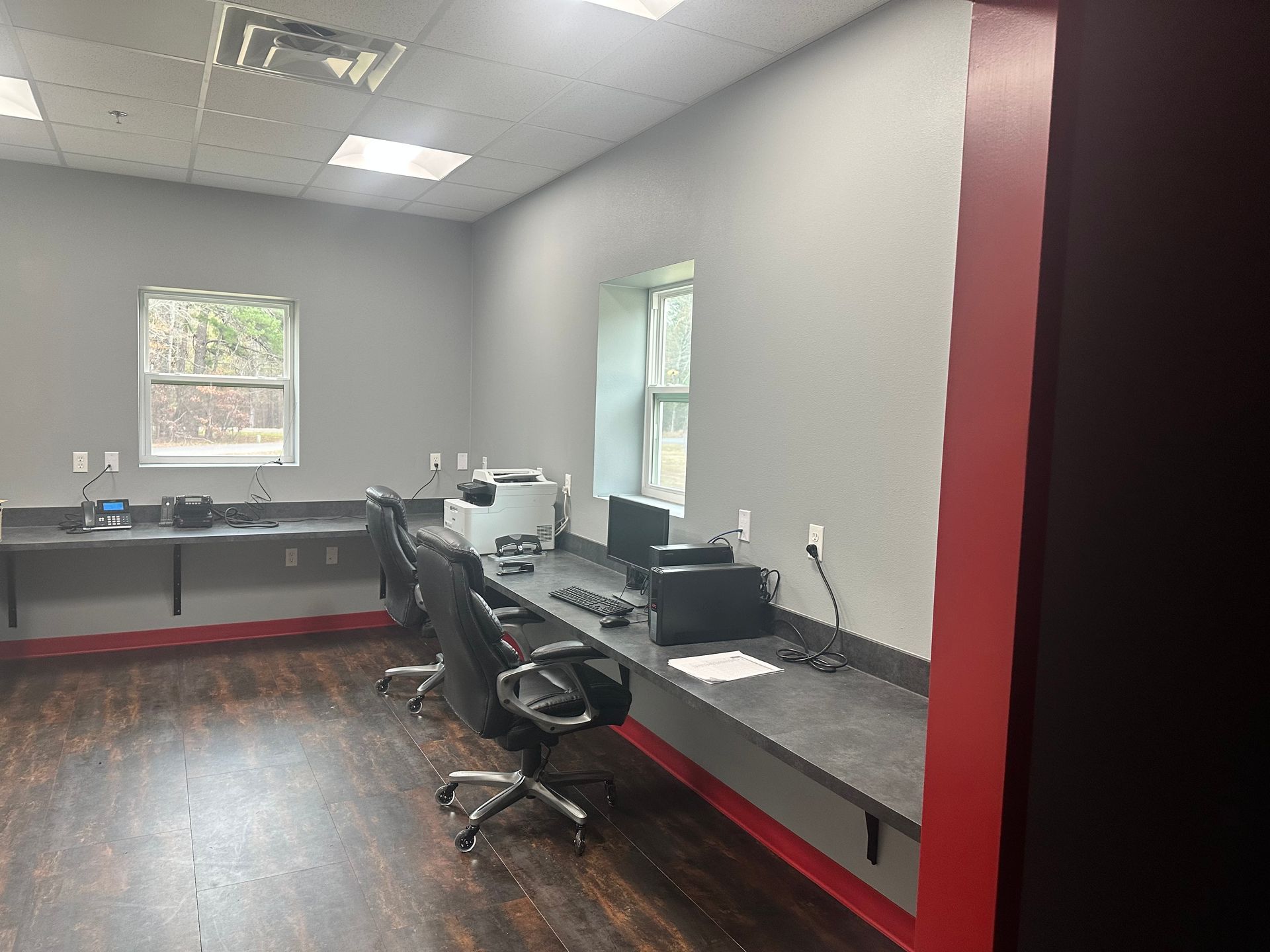 A room with a lot of desks and chairs and a printer.