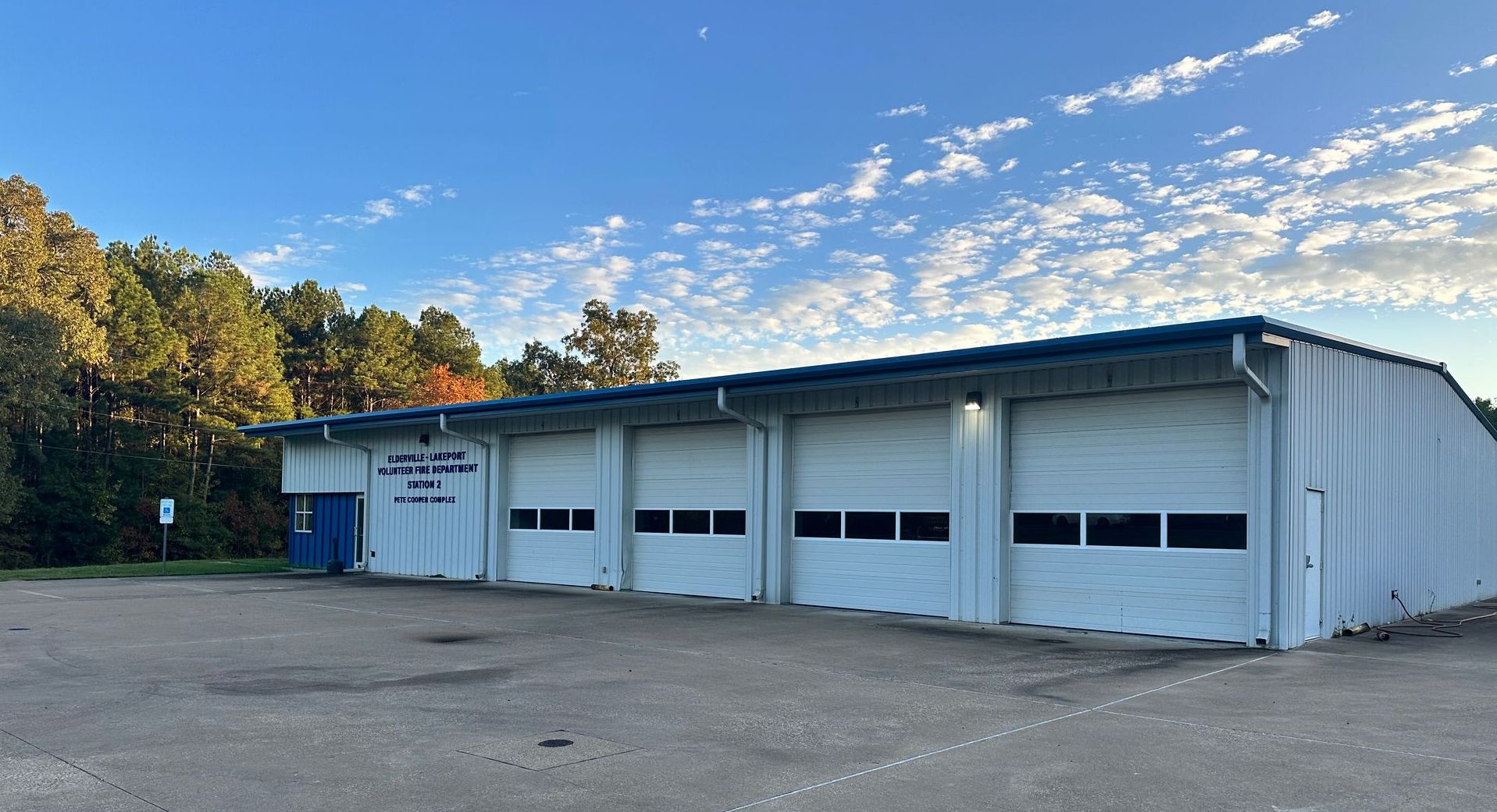 A large white building with a lot of garage doors and a blue roof.