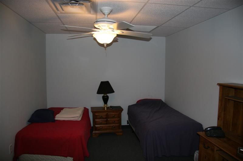 A bedroom with two beds and a ceiling fan