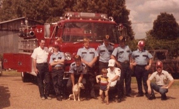 A group of firefighters posing in front of a red fire truck