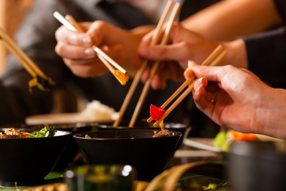 A Group Of People Are Eating Food With Chopsticks From Bowls — One Thai Cuisine & Noodle Bar In Kirwan, QLD