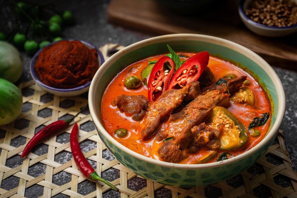 A Bowl Of Red Curry With Meat And Vegetables On A Table — One Thai Cuisine & Noodle Bar In Kirwan, QLD