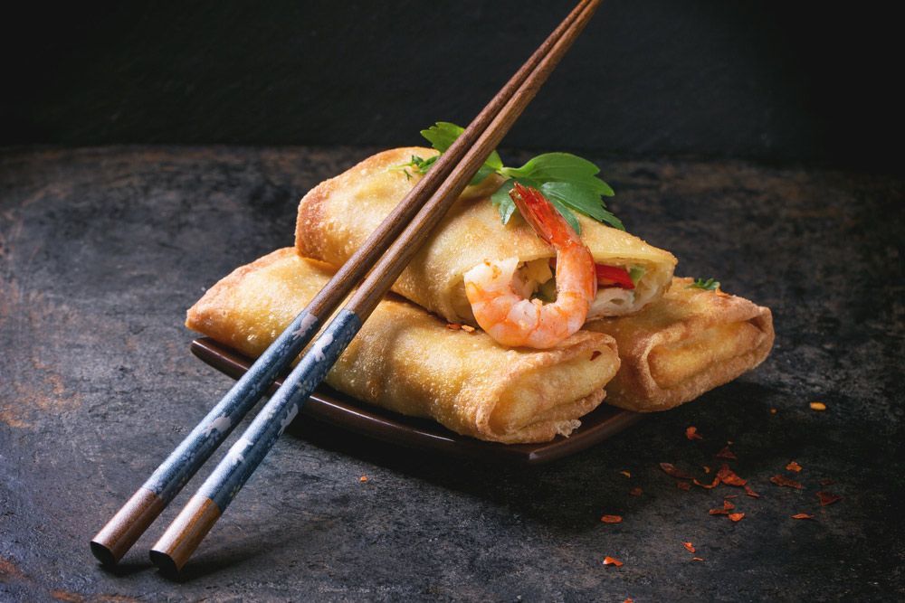 A Plate Of Spring Rolls With Shrimp And Chopsticks On A Table — One Thai Cuisine & Noodle Bar In Kirwan, QLD