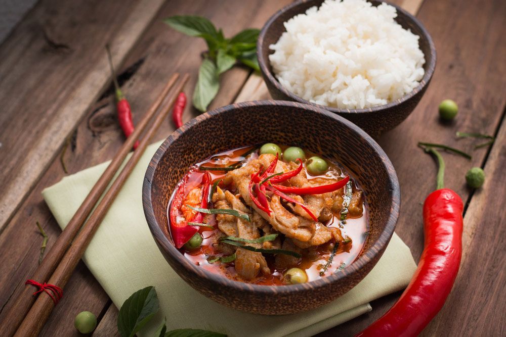 A Bowl Of Chicken Curry With Rice And Chopsticks On A Wooden Table — One Thai Cuisine & Noodle Bar In Kirwan, QLD