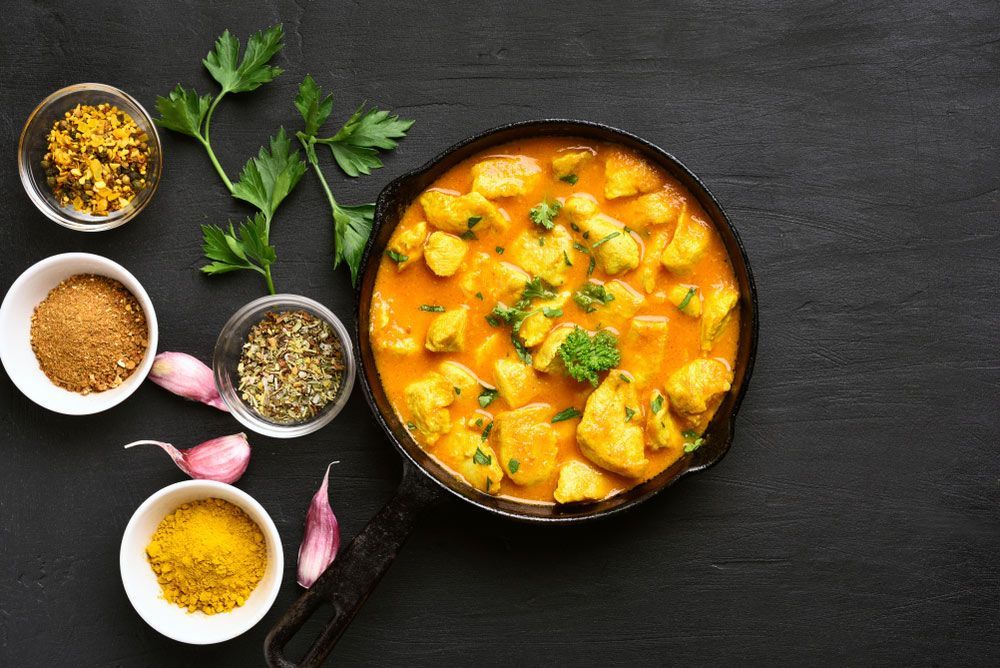 A Pan Filled With Chicken Curry Next To Bowls Of Spices — One Thai Cuisine & Noodle Bar In Kirwan, QLD