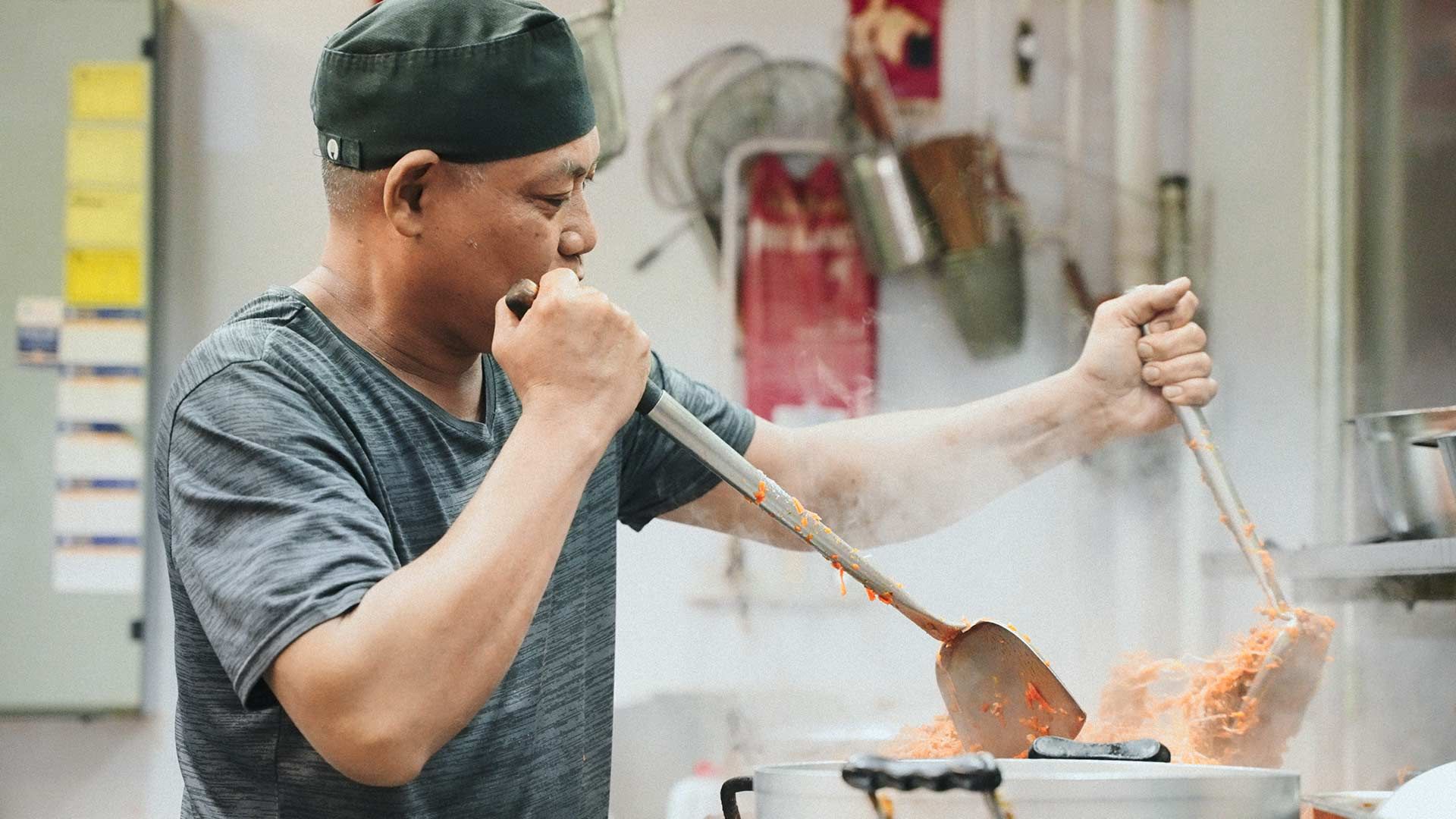 A Man is Cooking Food in a Kitchen With a Wooden Spatula — One Thai Cuisine & Noodle Bar In Kirwan, QLD
