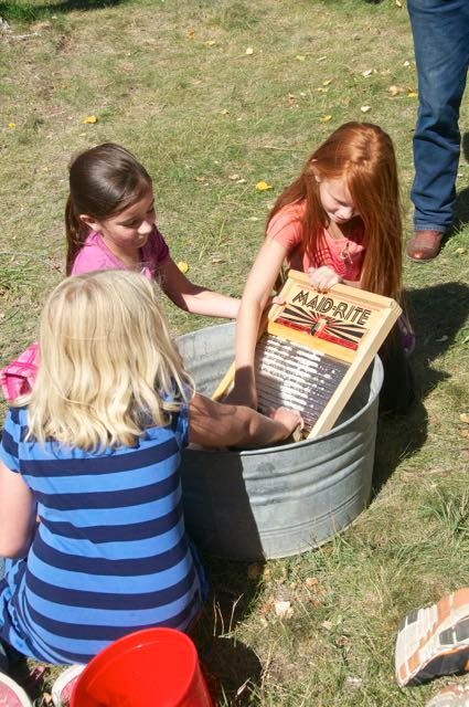 Three young girls are playing with a washboard outside