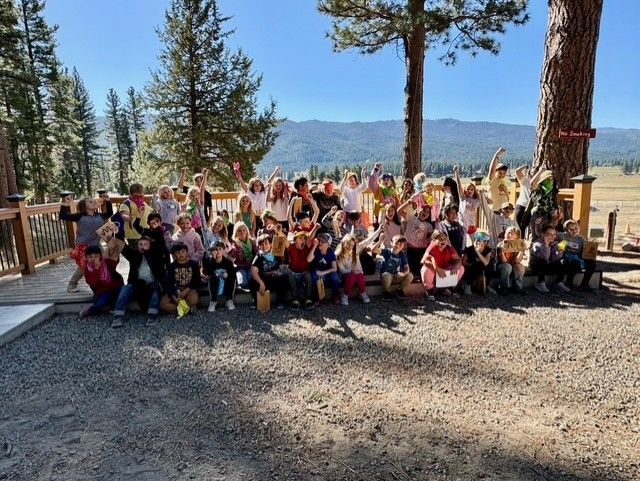A group of children are posing for a picture with their hands in the air.