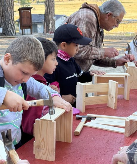 A group of children are hammering nails into wooden blocks.