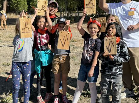 A group of children are posing for a picture while holding up wooden signs.