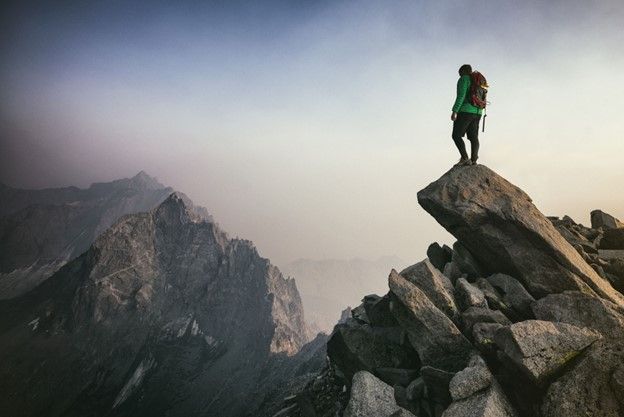 A person with a backpack is standing on top of a rocky mountain.