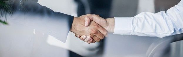 A close up of two people shaking hands in an office.