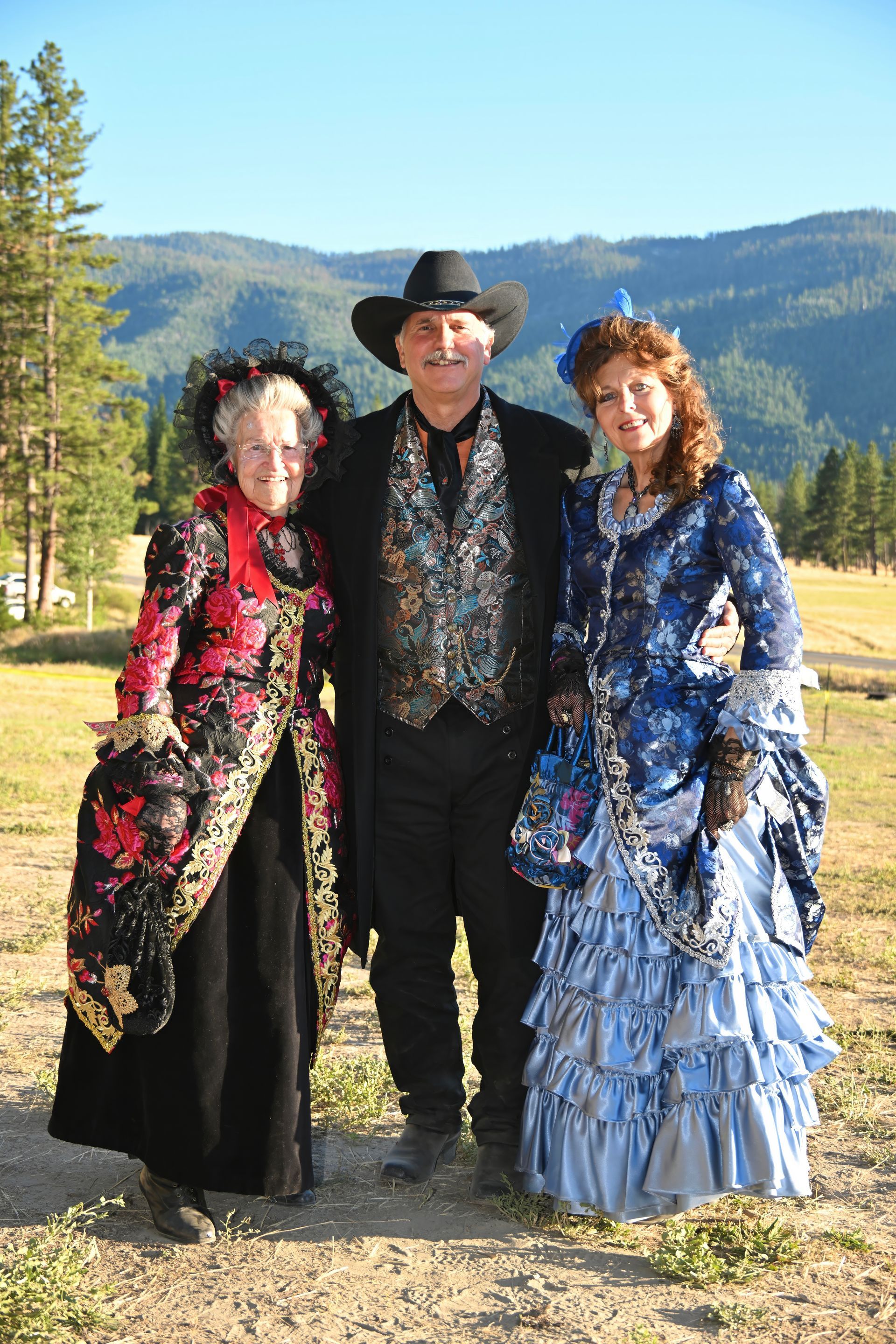 A man and two women are posing for a picture in a field.