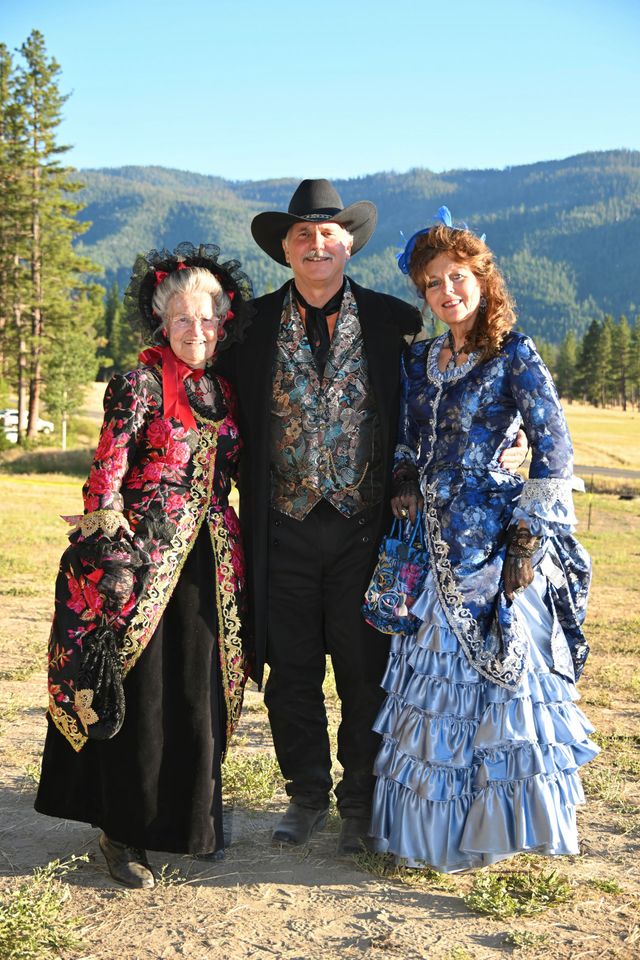 A man and two women are posing for a picture in a field.