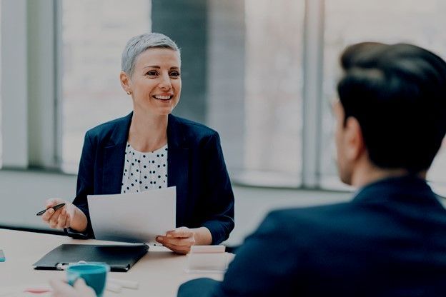 A woman is sitting at a table talking to a man.