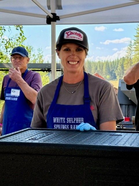 A woman wearing an apron that says white sulphur springs on it