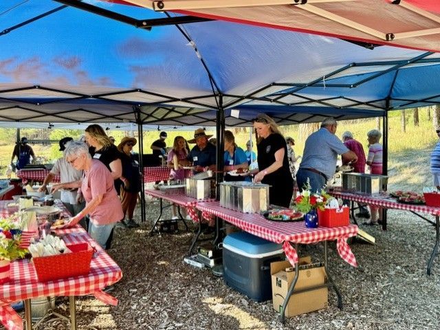 A group of people are standing around tables under tents.