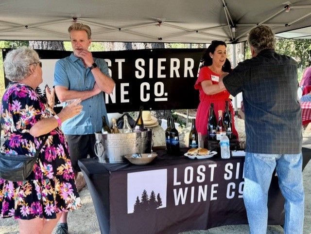 A group of people standing around a table that says lost sierra wine co.