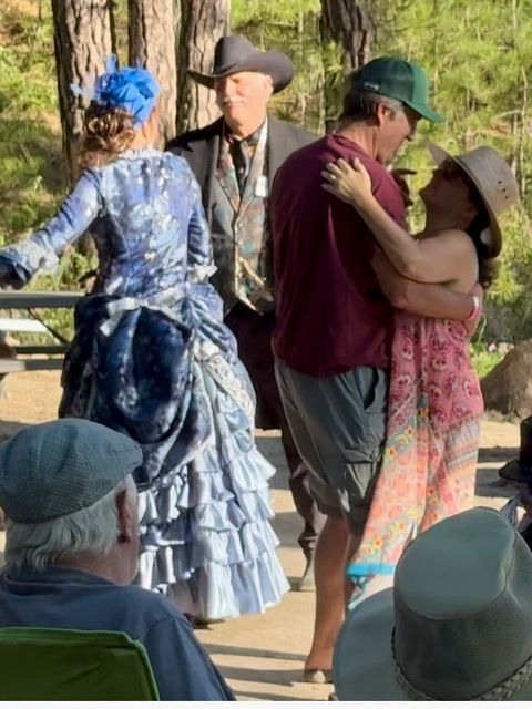 A woman in a blue dress is dancing with a man in a cowboy hat.